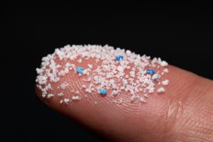Microplastics.Small Plastic pellets on the finger. Concept of microplastics in bottled water.